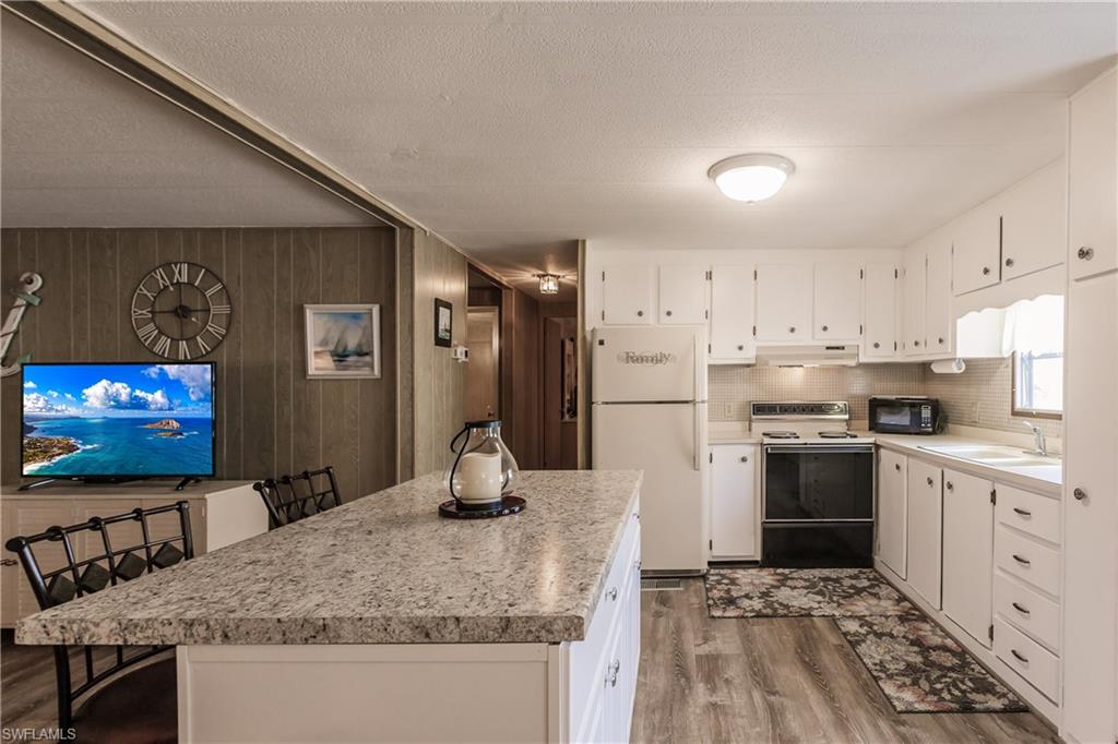 10100 Burnt Store Road, Unit 104 Punta Gorda, FL 33950 - Photo 14 of 46 Kitchen with wood-type flooring, white appliances, white cabinetry, and and luxury vinyl plank flooring
