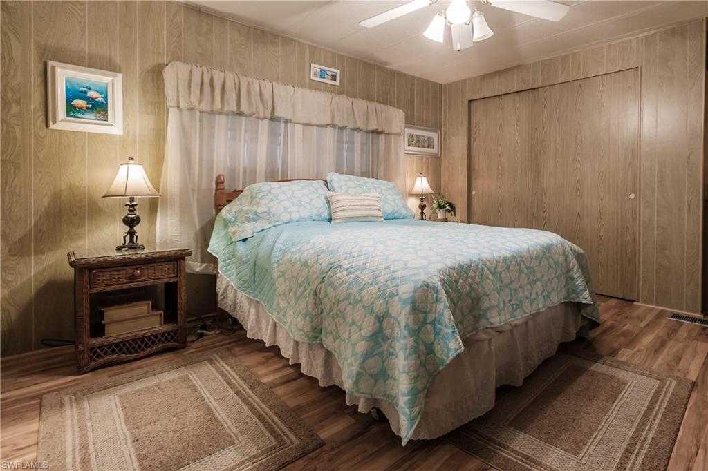 10100 Burnt Store Road, Unit 104 Punta Gorda, FL 33950 - Photo 18 of 46 Primary retreat with laminate / wood-style floors, ceiling fan, wood walls, and a closet