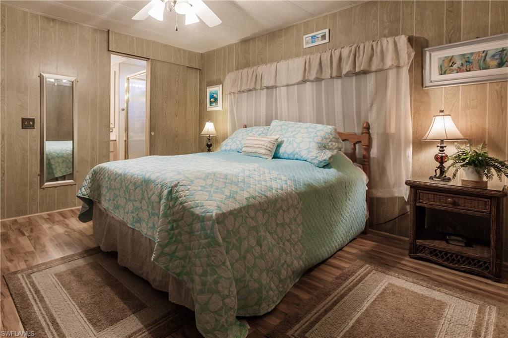 10100 Burnt Store Road, Unit 104 Punta Gorda, FL 33950 - Photo 19 of 46 Bedroom featuring laminate / wood-style floors, ceiling fan, and wood walls