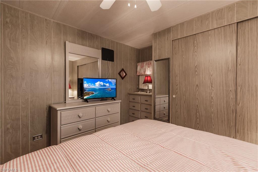 10100 Burnt Store Road, Unit 104 Punta Gorda, FL 33950 - Photo 24 of 46 Peaceful bedroom with ceiling fan, wooden walls, and windows