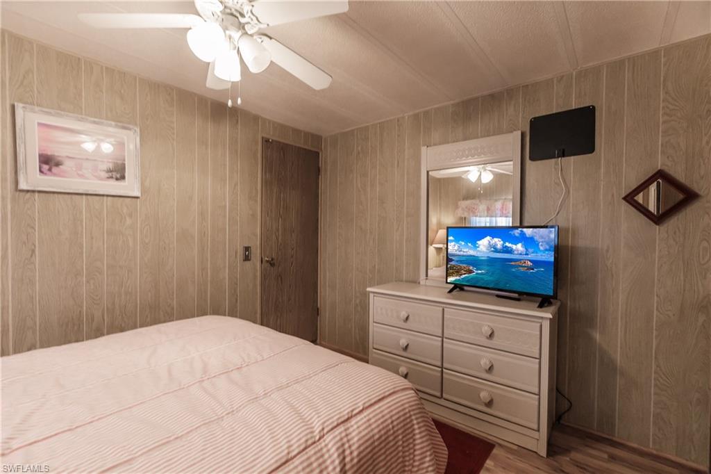 10100 Burnt Store Road, Unit 104 Punta Gorda, FL 33950 - Photo 25 of 46 Bedroom with laminate / wood-style floors, ceiling fan, and wood walls