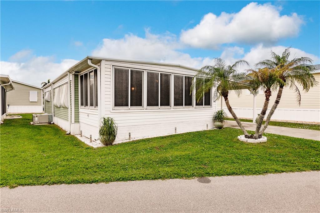 10100 Burnt Store Road, Unit 104 Punta Gorda, FL 33950 - Photo 28 of 46 View of property exterior with a yard and palm tree