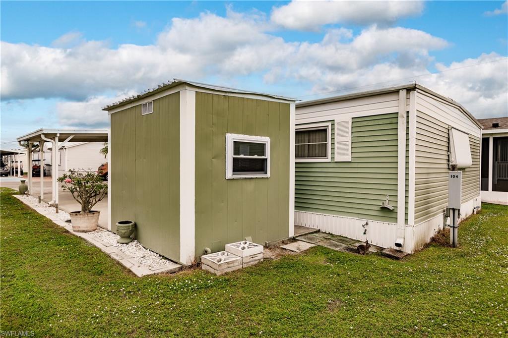 10100 Burnt Store Road, Unit 104 Punta Gorda, FL 33950 - Photo 29 of 46 View of side of property with a storage shed and lawn