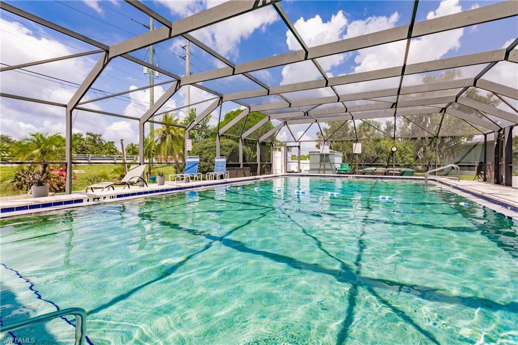 View of heated, fully caged community swimming pool with a lanai