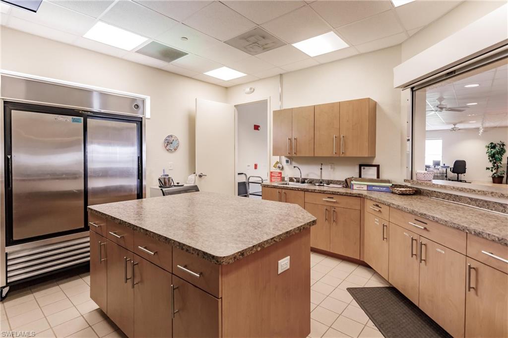 10100 Burnt Store Road, Unit 104 Punta Gorda, FL 33950 - Photo 41 of 46 Kitchen featuring ceiling fan, stainless steel built in fridge, a kitchen island, and light tile patterned flooring