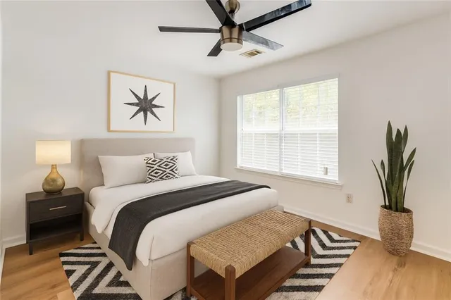 an empty room with wooden floor fan and windows