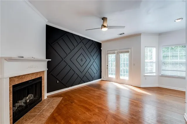 a view of a livingroom with wooden floor a ceiling fan and kitchen space