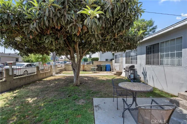 a view of a backyard with table and chairs with wooden fence and plants