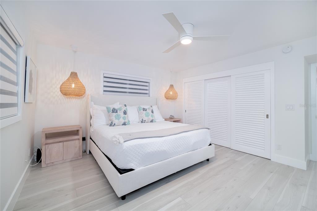 1104 Beach Trail, Unit 1 Indian Rocks Beach, FL 33785 - Photo 15 of 24 a white bed sitting in a bedroom next to a window and a chandelier