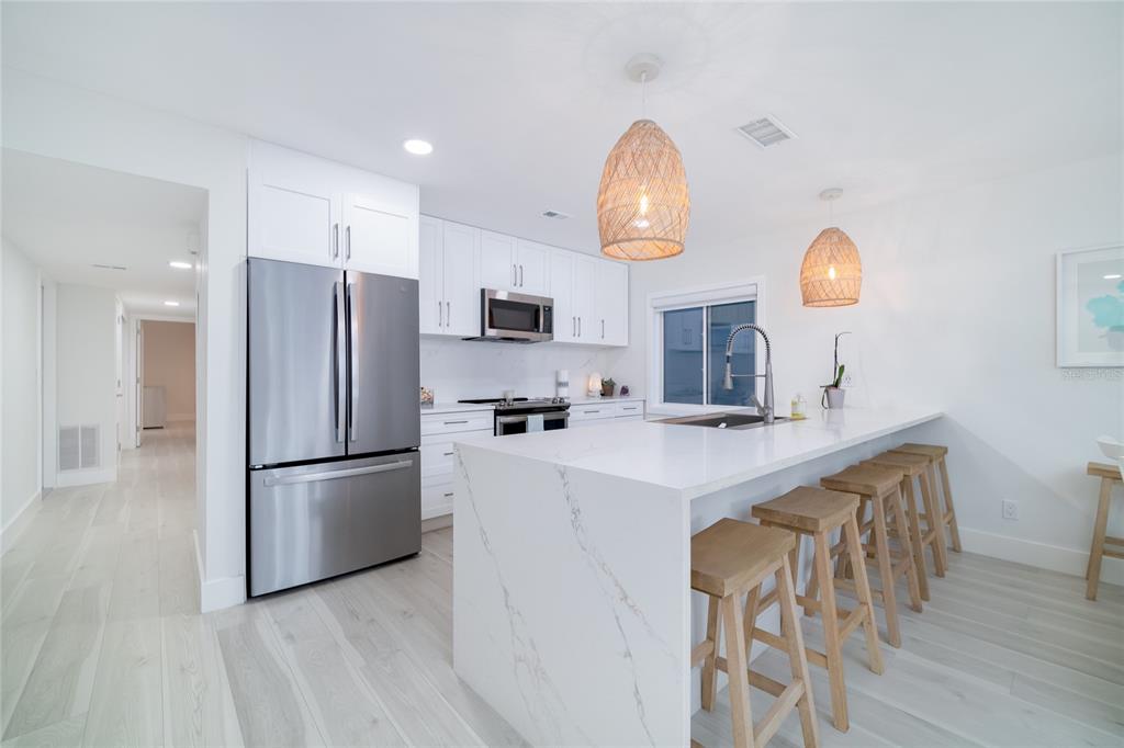 1104 Beach Trail, Unit 1 Indian Rocks Beach, FL 33785 - Photo 9 of 24 a kitchen with kitchen island stainless steel appliances a refrigerator stove and microwave