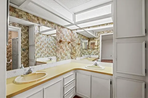 an empty room with wooden floor chandelier fan and windows