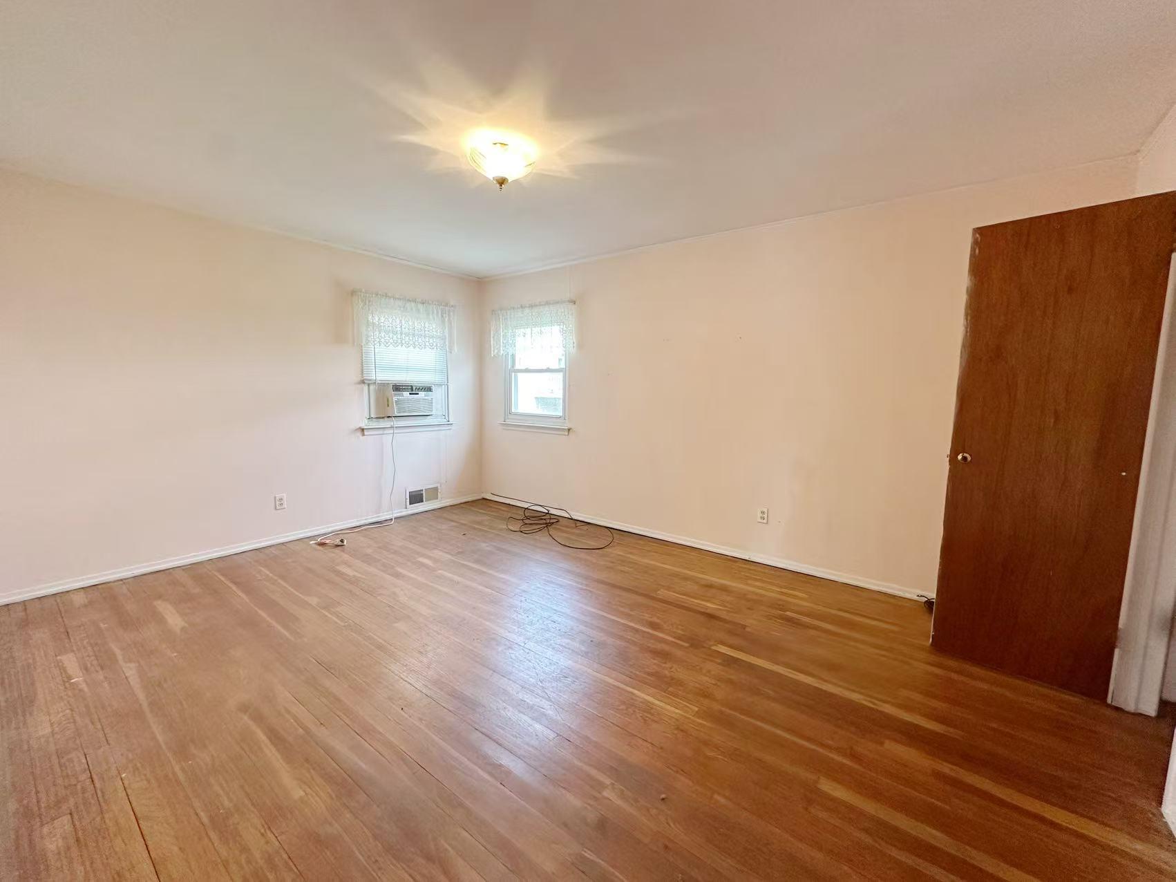 23-11 Whitestone Expressway Queens, NY 11357 - Photo 3 of 10 an empty room with wooden floor and windows