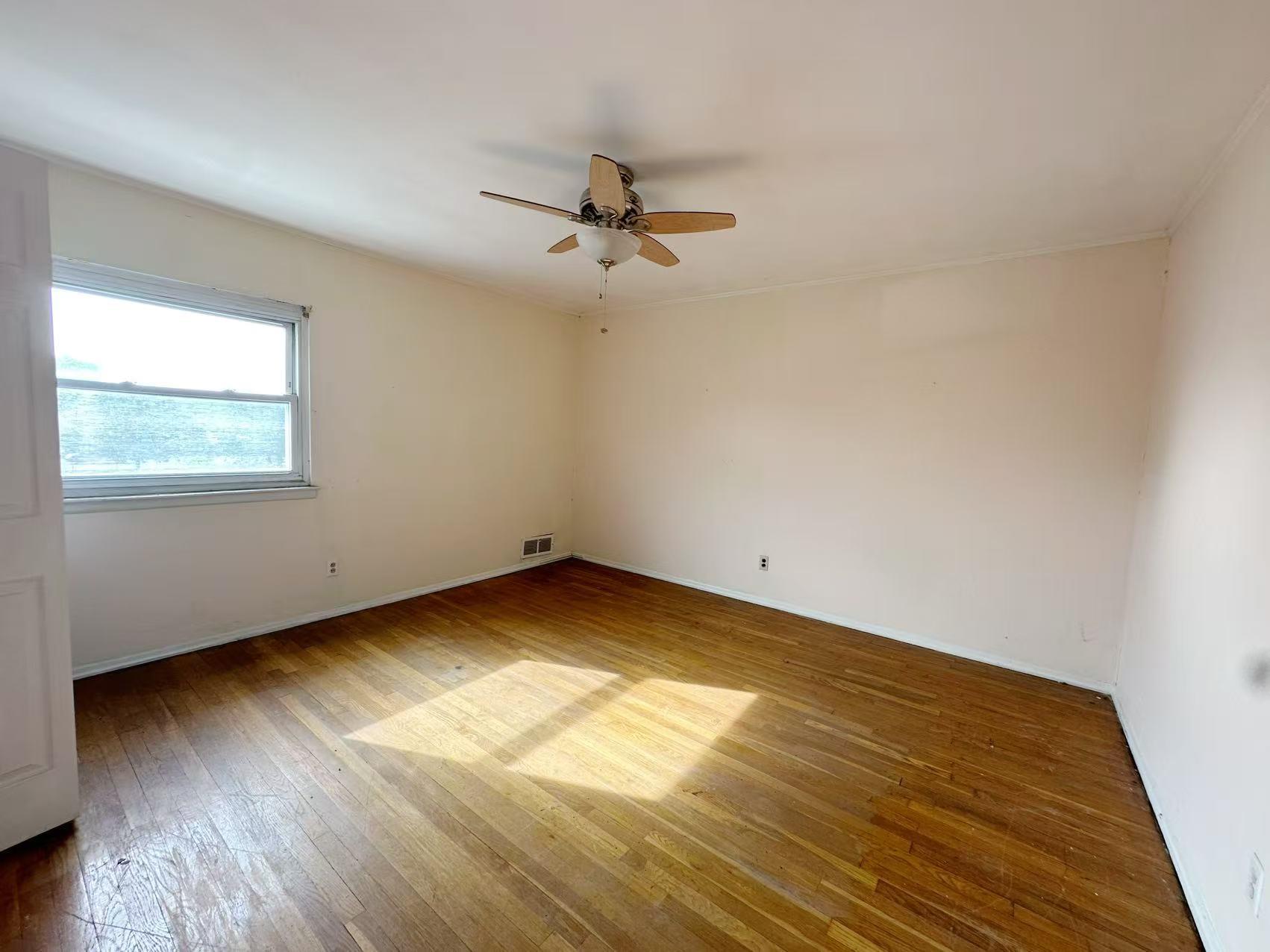 23-11 Whitestone Expressway Queens, NY 11357 - Photo 8 of 10 an empty room with wooden floor ceiling fan and windows