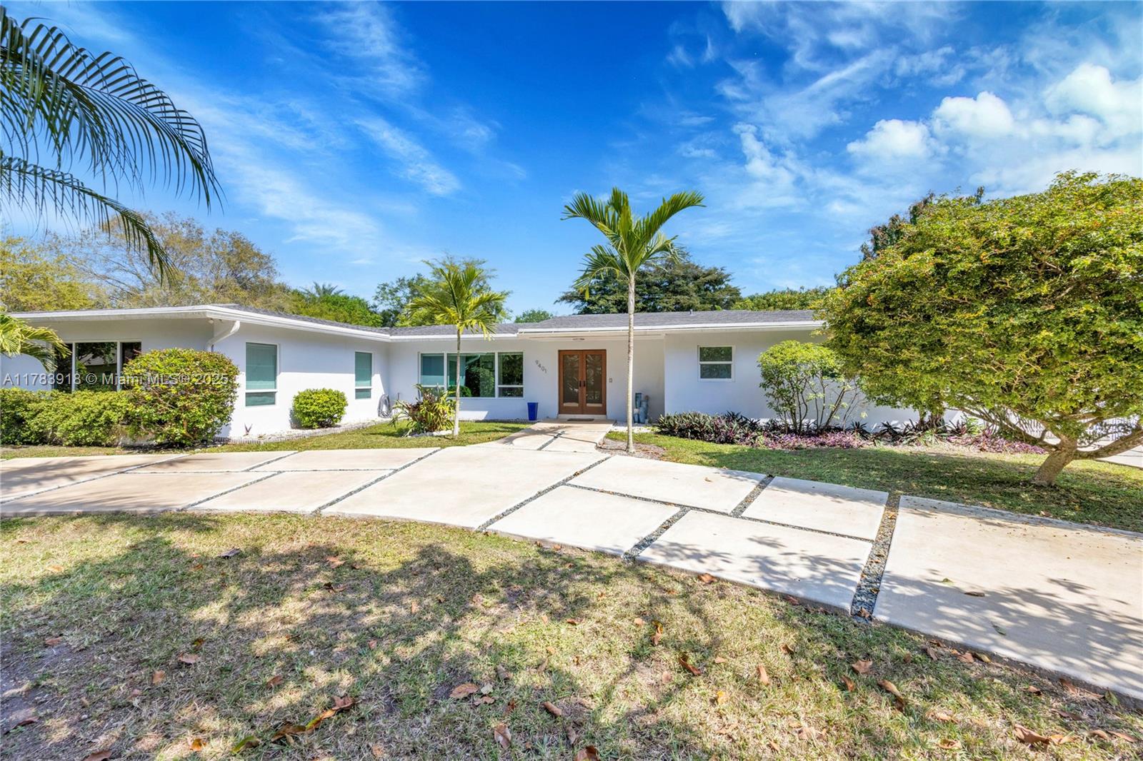 9401 Southwest 69th Court Pinecrest, FL 33156 - Photo 2 of 39 a front view of a house with a yard and potted plants