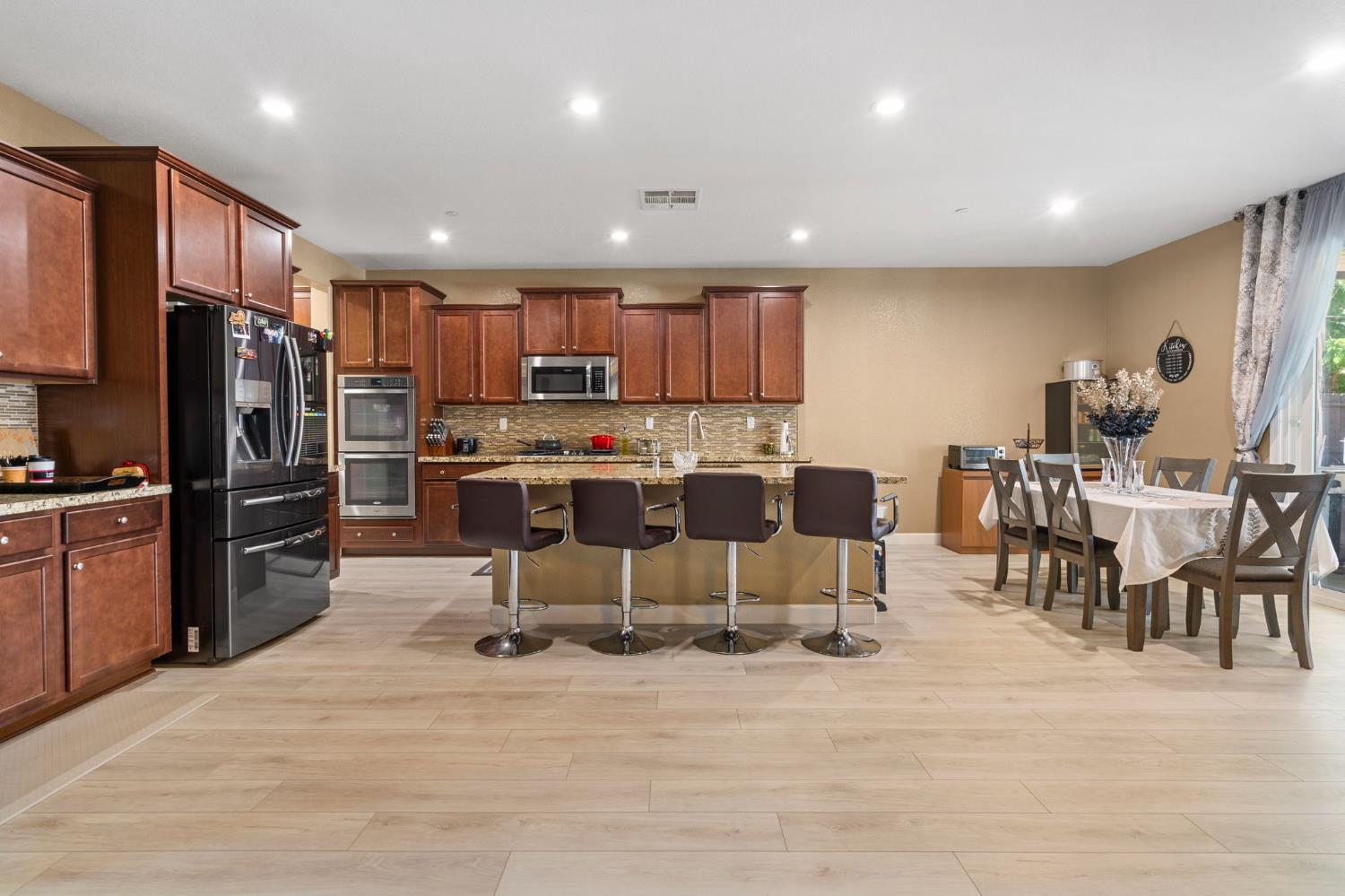 2317 Mathar Drive Manteca, CA 95337 - Photo 13 of 48 a kitchen with stainless steel appliances kitchen island granite countertop a refrigerator and a dining table