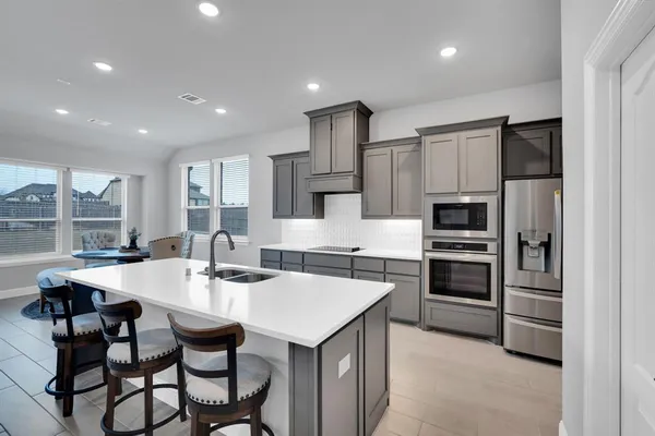 a kitchen with stainless steel appliances kitchen island granite countertop a table chairs microwave and refrigerator