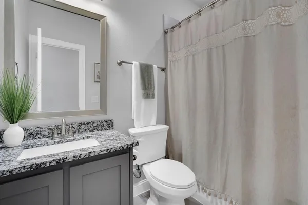 a bathroom with a granite countertop sink toilet and a mirror
