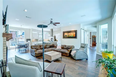 a living room with furniture kitchen view and a wooden floor