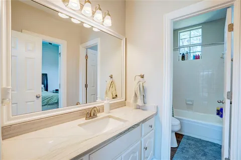 a bathroom with a granite countertop sink a toilet and shower