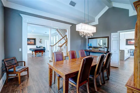 a dining room with wooden floor a chandelier a wooden table and chairs