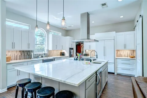 a kitchen with granite countertop a sink a center island stainless steel appliances and cabinets