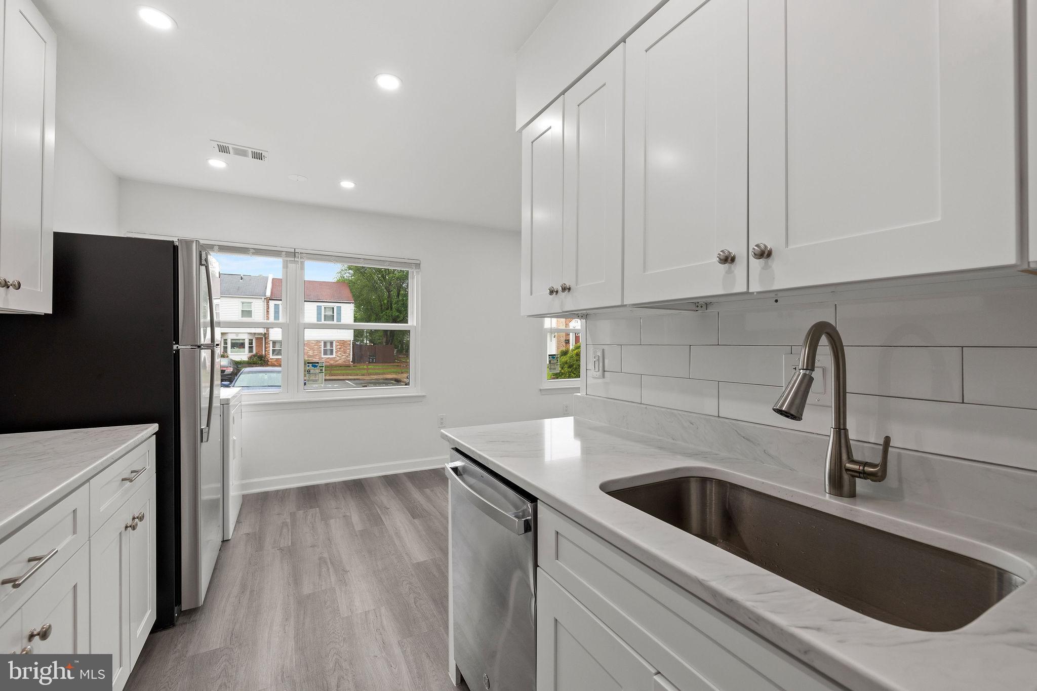 8157 Community Drive Manassas, VA 20109 - Photo 22 of 37 a kitchen with a sink dishwasher a refrigerator and cabinets with wooden floor