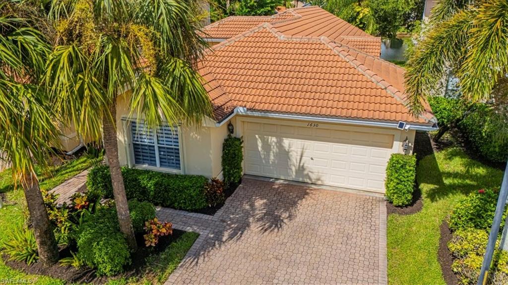 1630 Triangle Palm Terrace Naples, FL 34119 - Photo 2 of 24 a front view of a house with a yard and garage
