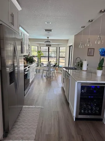 a kitchen with stainless steel appliances granite countertop a refrigerator a sink dishwasher a stove and a dining table with wooden floor