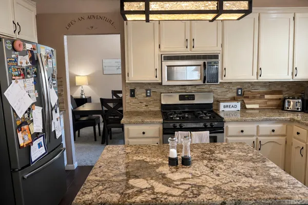 a kitchen with stainless steel appliances granite countertop a stove a sink a microwave and a refrigerator