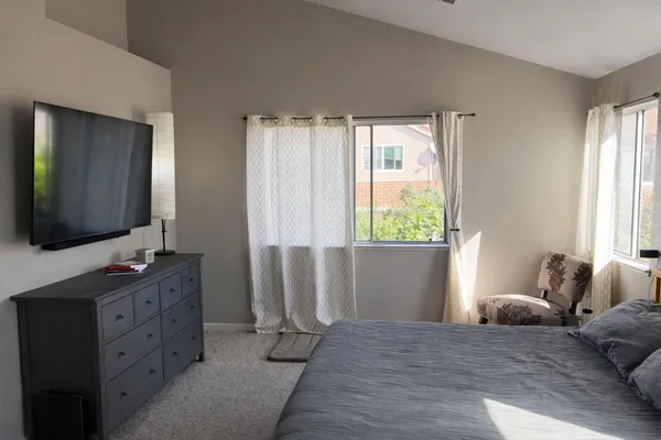 a bedroom with a large bed and a flat tv screen on dresser