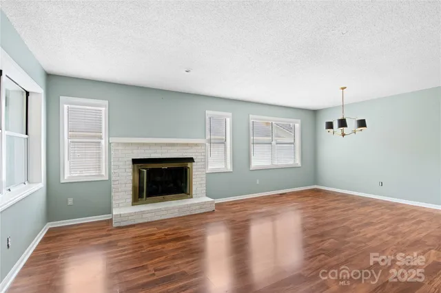 a view of empty room with wooden floor and fireplace