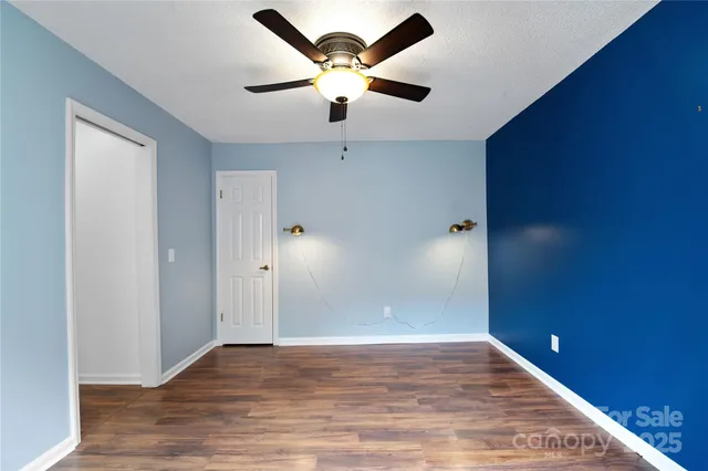 an empty room with wooden floor and a ceiling fan