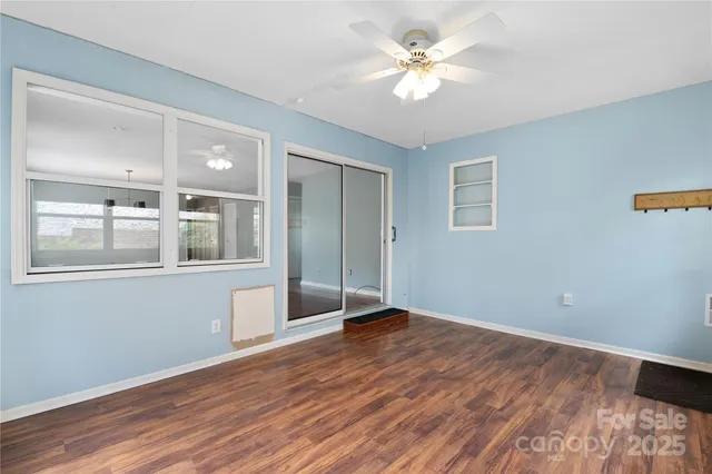 a view of an empty room with window and wooden floor