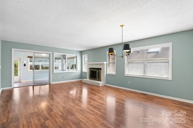 a view of an empty room with window and wooden floor