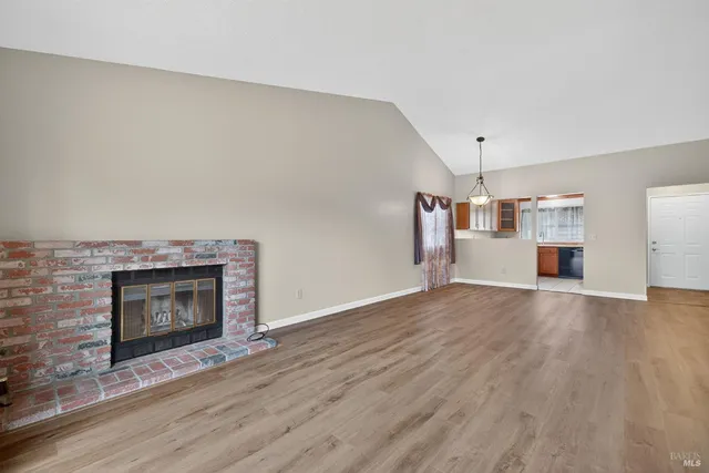 an empty room with wooden floor fireplace and windows