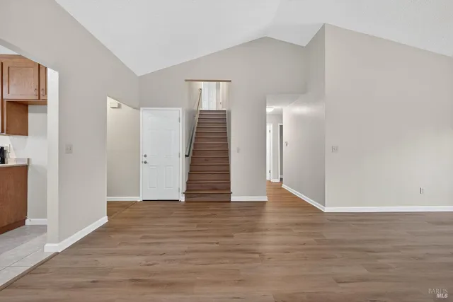 a view of an empty room with wooden floor and a bathroom