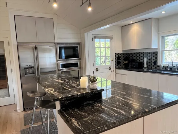 a kitchen with kitchen island granite countertop a stove refrigerator and microwave