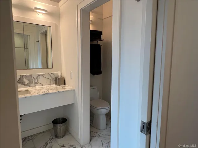 a bathroom with a granite countertop sink and a toilet