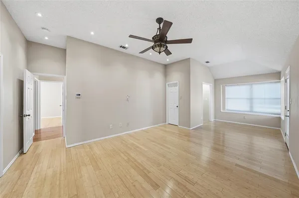 a view of empty room with wooden floor and ceiling fan