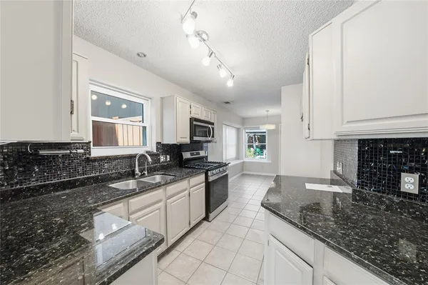 a large kitchen with granite countertop a sink and white cabinets