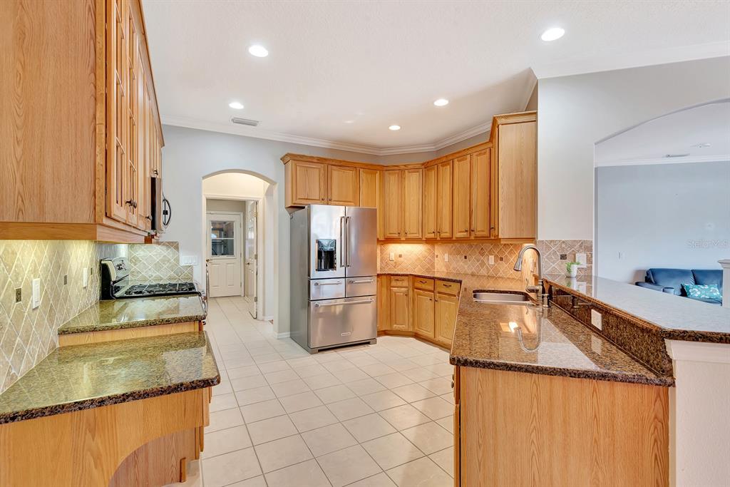 7344 Arrowhead Run Lakewood Ranch, FL 34202 - Photo 17 of 24 a kitchen with a sink a refrigerator and a stove top oven