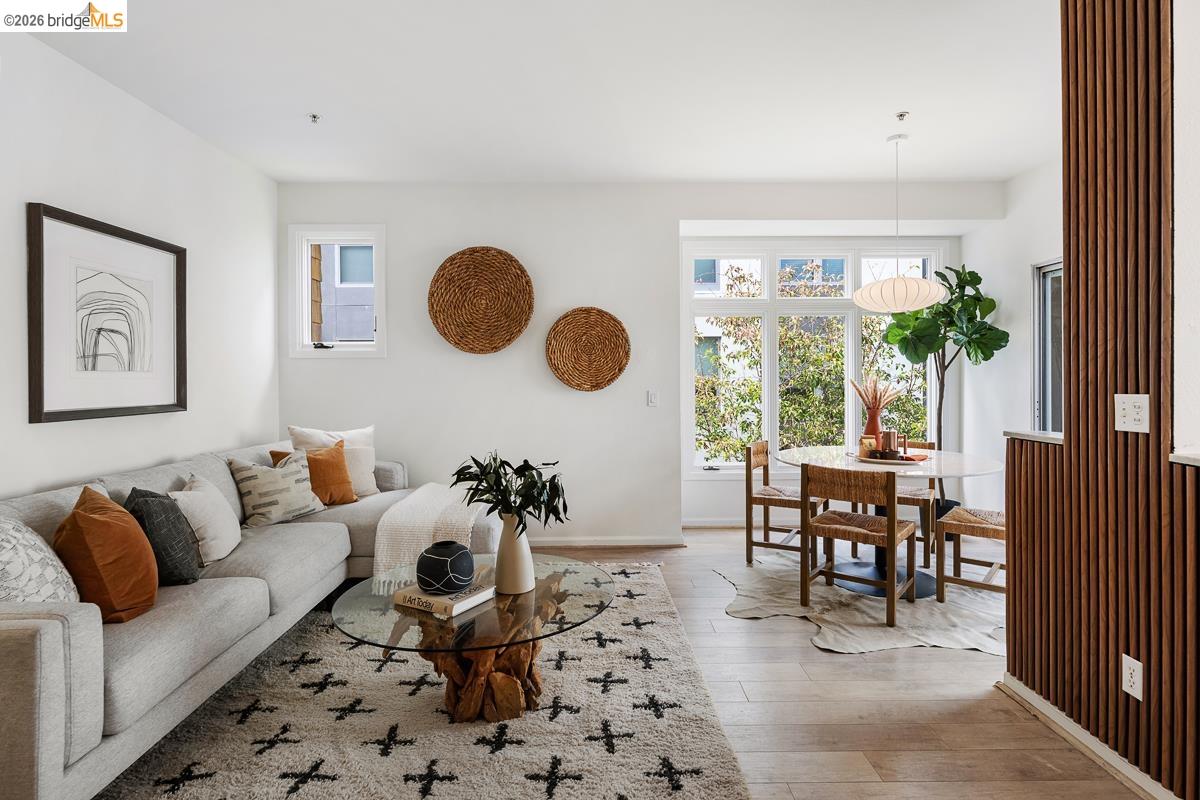 2029 Channing Way, Unit 3D Berkeley, CA 94704 - Photo 2 of 54 Open-concept living area featuring light wood-finish flooring, white walls, a large bay window, and a vertical wood slat wall accent