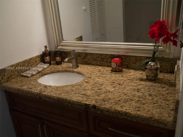 a bathroom with a granite countertop sink and a mirror