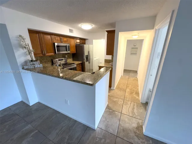a kitchen with kitchen island granite countertop a sink stove and cabinets
