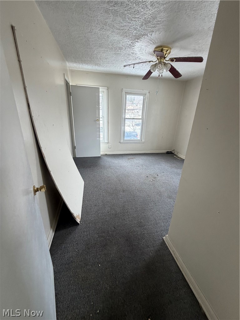55060 National Road Bridgeport, OH 43912 - Photo 9 of 14 Unfurnished room with ceiling fan, a textured ceiling, and dark carpet