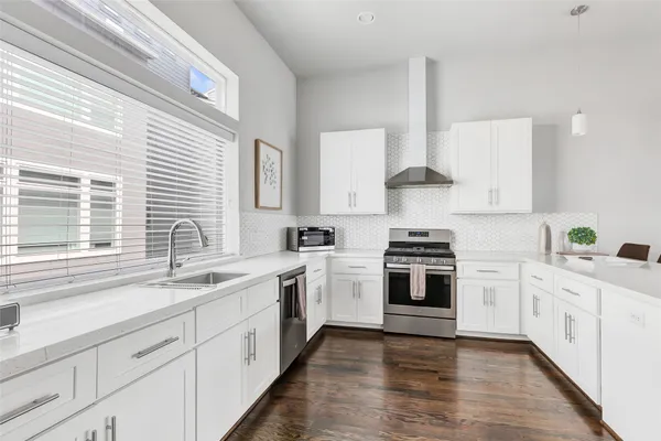 a kitchen with stainless steel appliances granite countertop white cabinets a stove a sink and a window