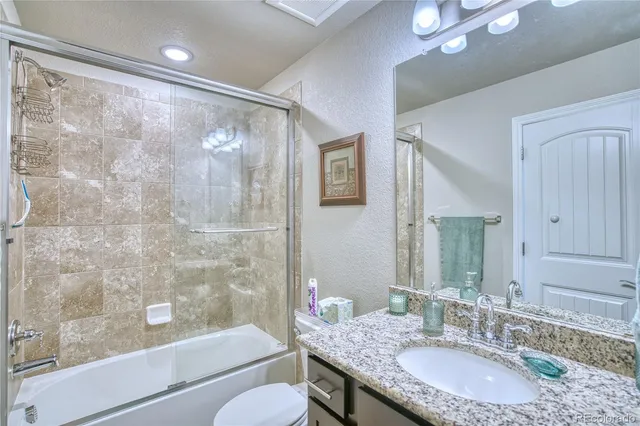 a bathroom with a granite countertop sink a mirror a bathtub and shower