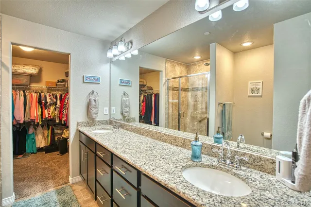 a bathroom with a granite countertop double vanity sink and a mirror