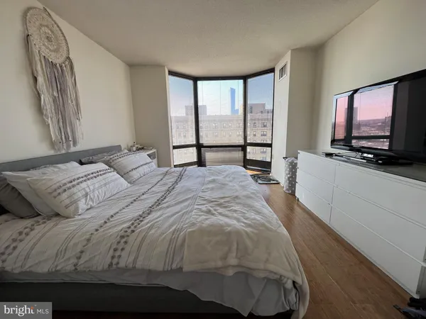 a bedroom with a large bed and a flat tv screen on dresser