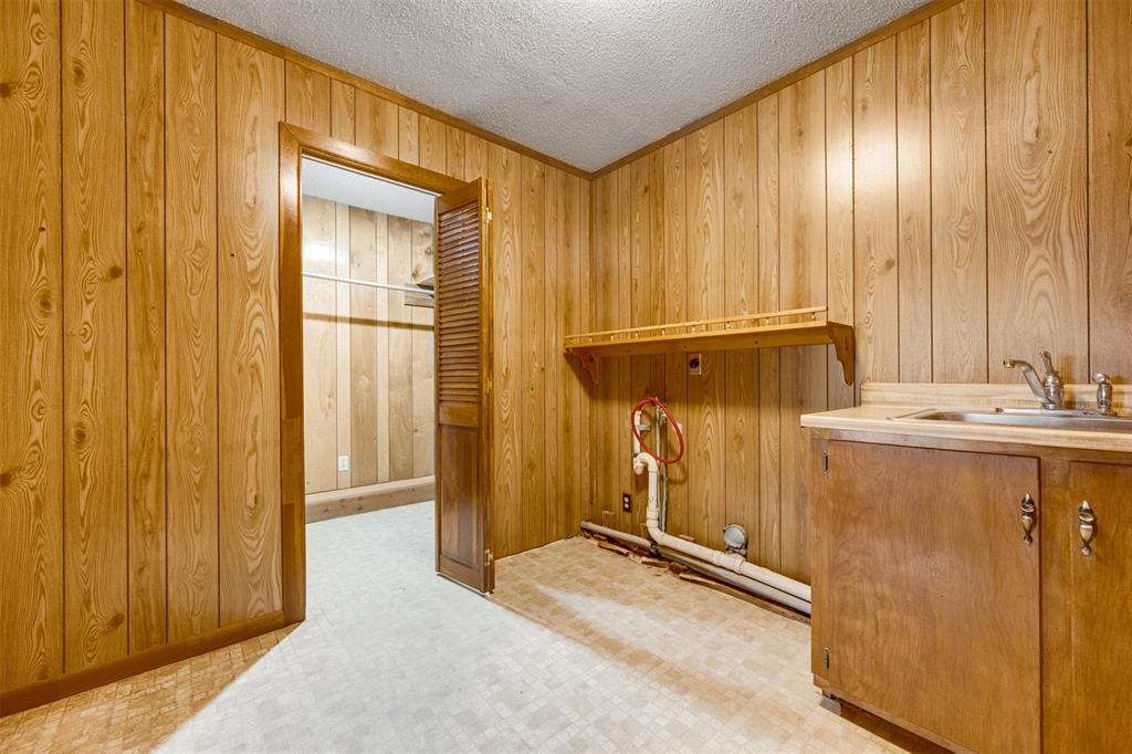 8798 Hill N Dale Road Tyler, TX 75709 - Photo 23 of 31 Utility room featuring wood-finish paneling, a built-in countertop with an integrated sink, base cabinetry, and a wall-mounted shelf